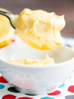 Close up thick and creamy golden mayonnaise on a spoon showing texture.