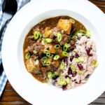 Overhead Jamaican curry goat served with rice and peas featuring a title overlay.