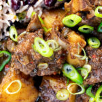 Overhead close-up Jamaican goat curry served with rice and peas.