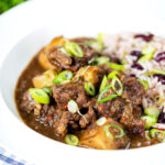 Jamaican curry goat served with rice and peas featuring a title overlay.