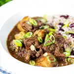 Jamaican curry goat served with rice and peas featuring a title overlay.
