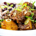 Close-up Jamaican curry goat served with rice and peas.