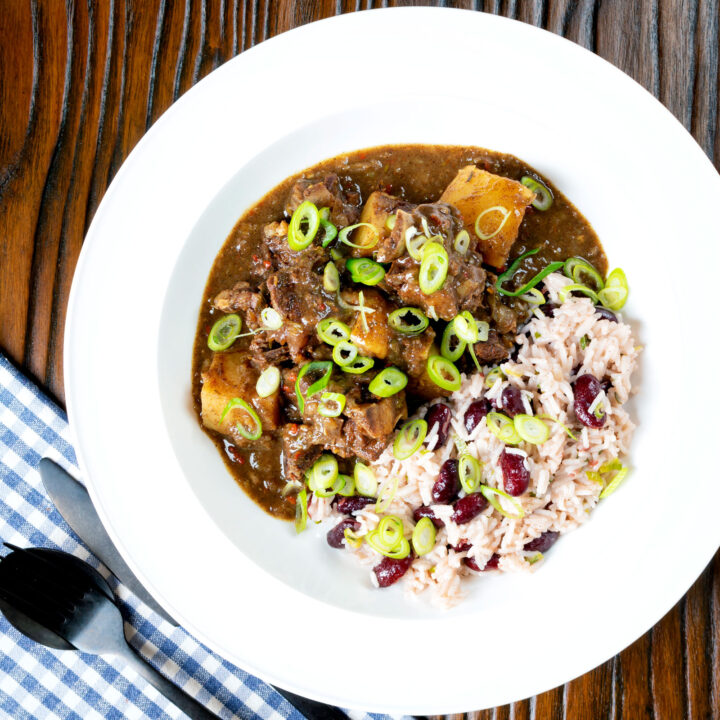 Spicy Jamaican inspired curry goat served with rice and peas garnished with spring onions.