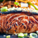 Close-up Korean inspired grilled salmon fillet served with noodles.