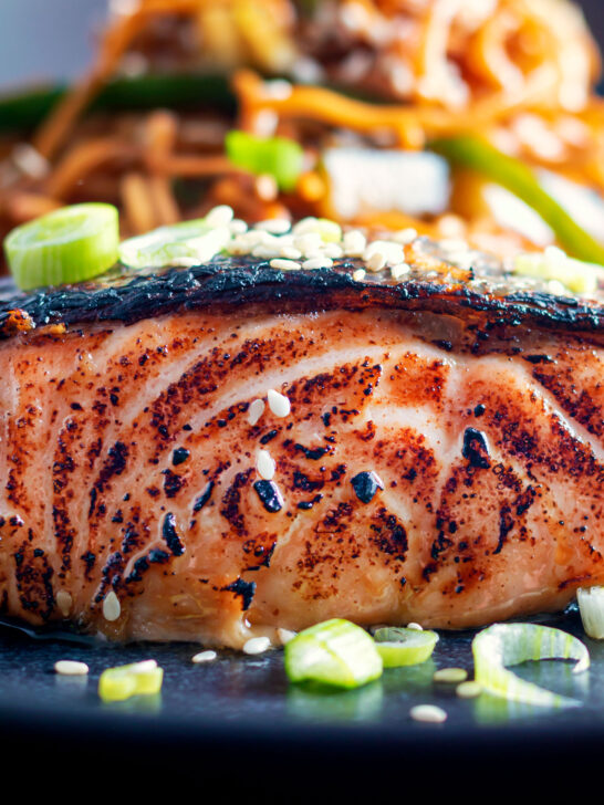 Close-up Korean inspired grilled salmon fillet served with noodles.