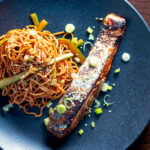 Overhead Korean inspired grilled salmon fillet served with noodles.