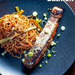 Overhead Korean inspired grilled salmon fillet served with noodles featuring a title overlay.