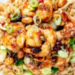 Overhead close-up kung pao king prawns or shrimp with peanuts and egg fried rice.