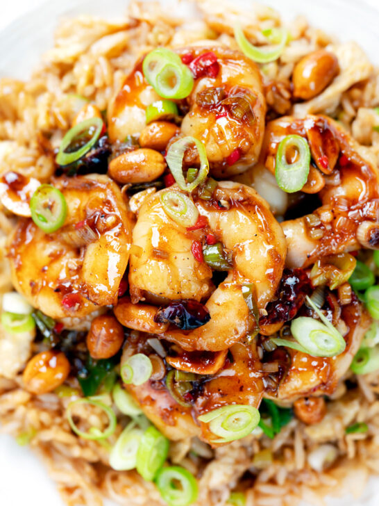 Overhead close-up kung pao king prawns or shrimp with peanuts and egg fried rice.