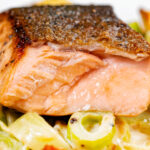 Close up pan fried salmon with crispy skin showing internal flesh colour when cooked.