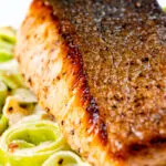 Close up pan fried salmon fillet with crispy skin served with creamed leeks.