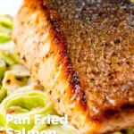 Close up pan fried salmon fillet with crispy skin served with creamed leeks featuring a title overlay.