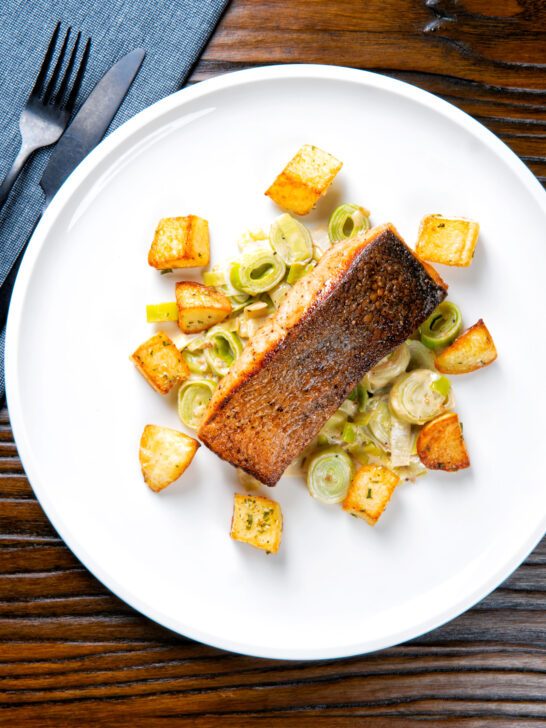 Overhead pan fried salmon fillet with crispy skin served with creamed leeks and parmentier potatoes.
