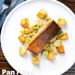 Overhead pan fried salmon fillet served with creamed leeks and parmentier potatoes featuring a title overlay.