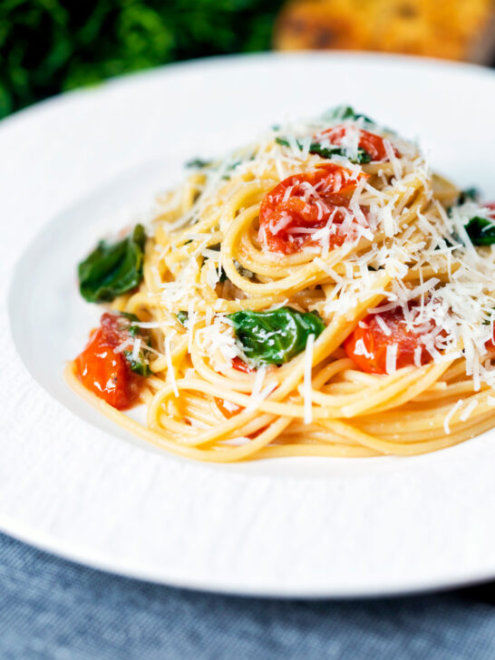 Roasted garlic pasta with tomatoes and spinach garnisheed with parmesan cheese.