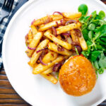 Overhead Chinese takeaway style salt and pepper chips served with a burger.