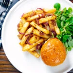 Overhead Chinese takeaway style salt and pepper chips served with a burger.