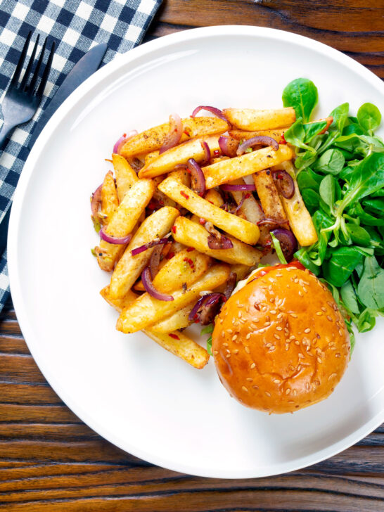 Overhead Chinese takeaway style salt and pepper chips served with a burger.