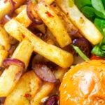 Overhead close-up Chinese takeaway style salt and pepper chips served with a burger.