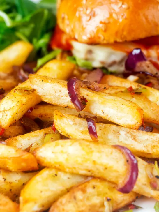 Close-up Chinese takeaway style salt and pepper chips served with a burger.