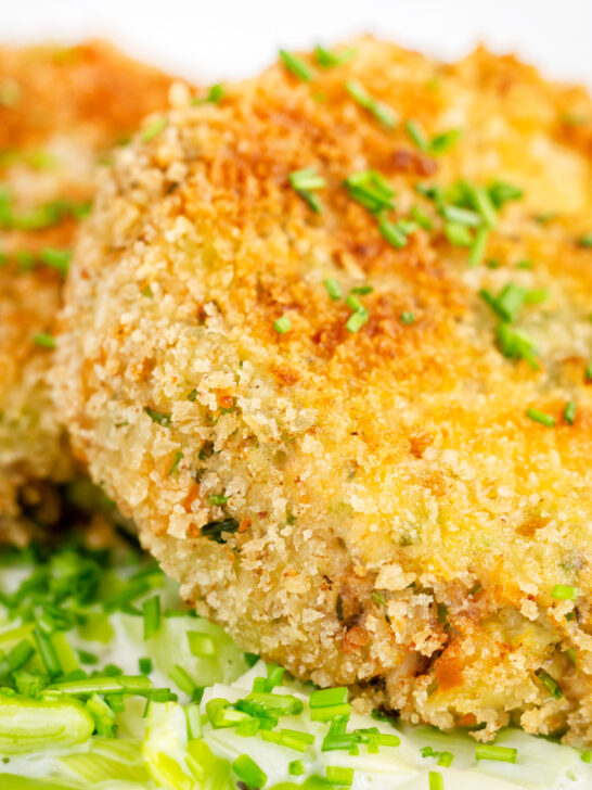 Close-up crispy golden salmon and sardine fish cakes served with creamed leeks.