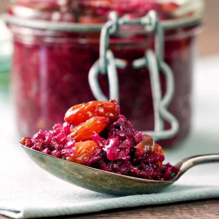 Sticky red cabbage chutney with golden raisins on a spoon.