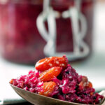 Close-up red cabbage chutney with large golden raisins on a spoon.