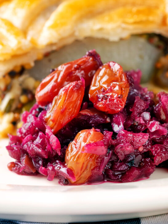 Close-up red cabbage chutney with large golden raisins served with a pie.