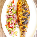 Overhead whole tandoori trout fish that has been cooked on a BBQ.