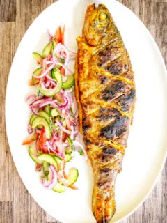 Overhead whole tandoori trout fish that has been cooked on a BBQ.