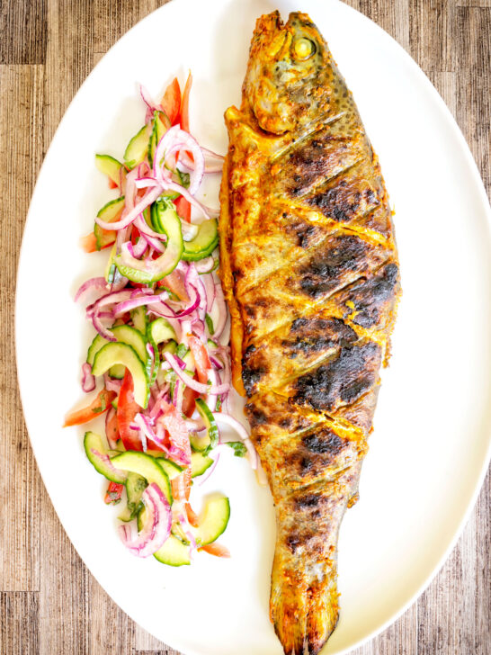 Overhead whole tandoori trout fish that has been cooked on a BBQ.
