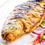 Whole tandoori trout fish that has been cooked on a BBQ.