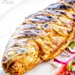 Whole tandoori trout fish that has been cooked on a BBQ featuring a title overlay.