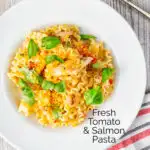 Overhead tomato and salmon fillet pasta with basil and crispy bread crumbs featuring a title overlay.