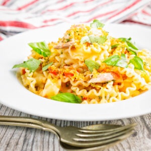 Tomato and fresh salmon pasta with golden breadcrumbs and torn basil leaves.