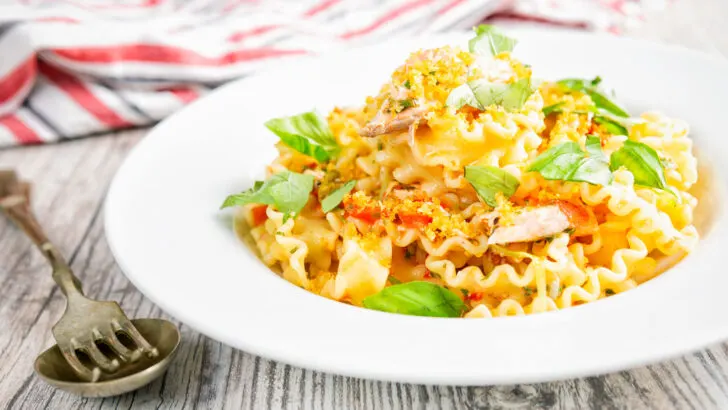Tomato and fresh salmon pasta with golden breadcrumbs and torn basil leaves.