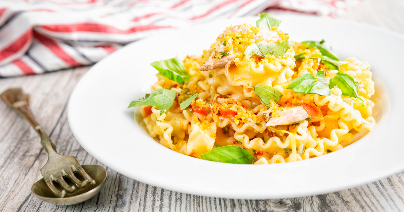Tomato and fresh salmon pasta with golden breadcrumbs and torn basil leaves.