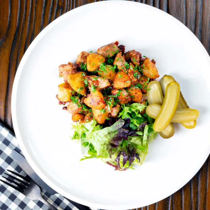 Hungarian Brassói aprópecsenye with crispy potatoes and pork tenderloin served with pickles.