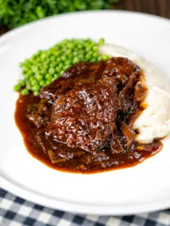 Braised steak and onions served with mashed potato and peas.