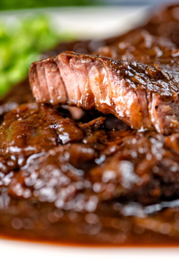 Close-up braised steak and onions showing the tender juicy meat.
