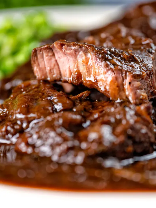 Close-up braised steak and onions showing the tender juicy meat.