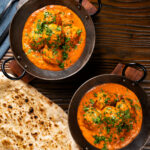 Overhead Indian chicken kofta or meatball curry served with naan bread.