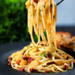 Spanish chorizo sausage and shredded leek pasta curled around a fork.