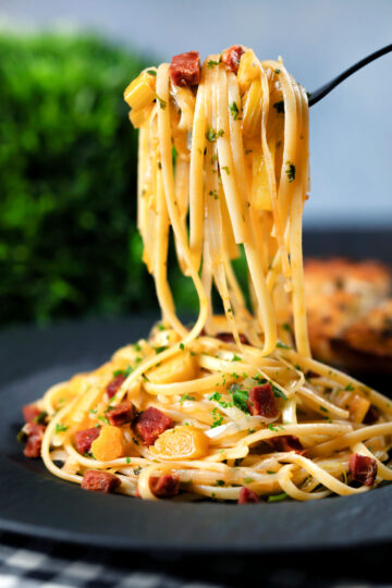 Spanish chorizo sausage and shredded leek pasta curled around a fork.