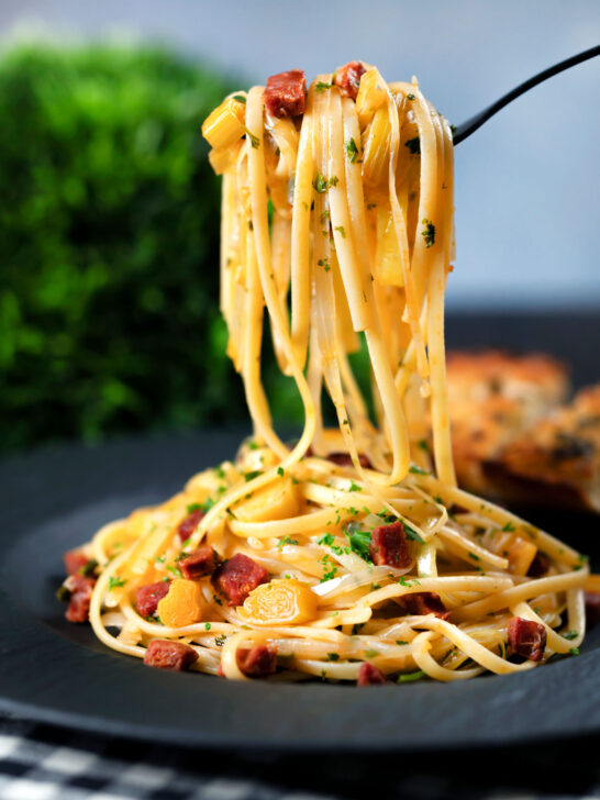 Spanish chorizo sausage and shredded leek pasta curled around a fork.