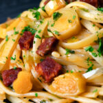 Close-up Spanish chorizo sausage and shredded leek pasta.