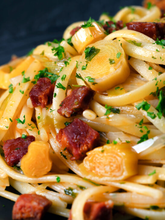 Close-up Spanish chorizo sausage and shredded leek pasta.