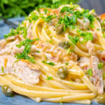 Close-up creamy lemon chicken pasta with capers and parsley.
