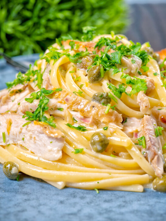 Close-up creamy lemon chicken pasta with capers and parsley.