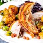 Slow roasted crispy pork belly Sunday lunch, with red cabbage, sprouts and roast potatoes featuring a title overlay.